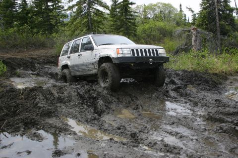 2003 Jeep TJ - A white Jeep Grand Cherokee navigates a muddy off-road trail.