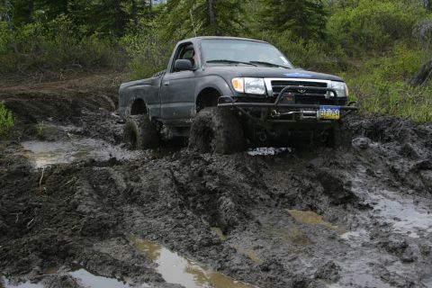 2003 Jeep TJ - A pickup truck navigates a challenging muddy terrain during an off-road event.