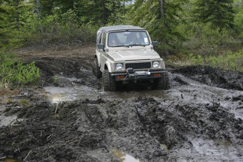 2003 Jeep TJ - A tan Suzuki Samurai navigates a challenging muddy off-road path.