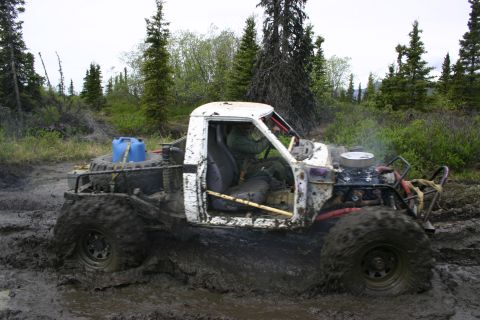 2003 Jeep TJ - Off-road pickup truck with oversized tires is stuck in thick mud during an event.