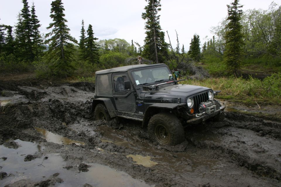 Black Jeep Wrangler TJ stuck in deep mud, front winch visible