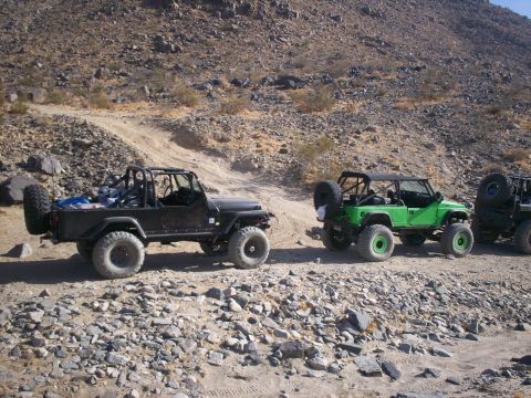 1987 Suzuki Samurai - Modified Jeeps navigate a rocky desert trail, ready for off-road adventure.