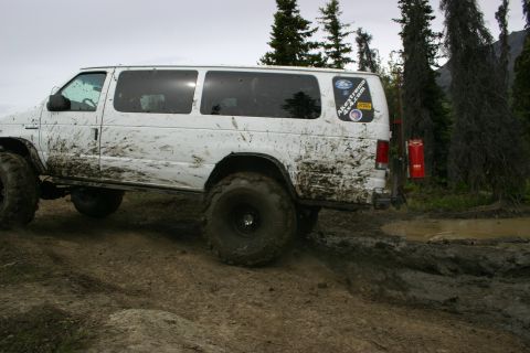 2003 Jeep TJ - White van with large tires navigating a muddy off-road course, displaying an 'AKextreme 4x4.com' sticker.