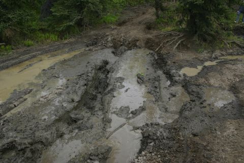 2003 Jeep TJ - A challenging muddy trail with deep tire tracks and puddles, indicating difficult off-road conditions.