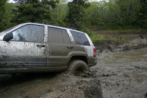 2003 Jeep TJ - A silver SUV, likely a 1999 Jeep Grand Cherokee, navigates a muddy off-road trail.