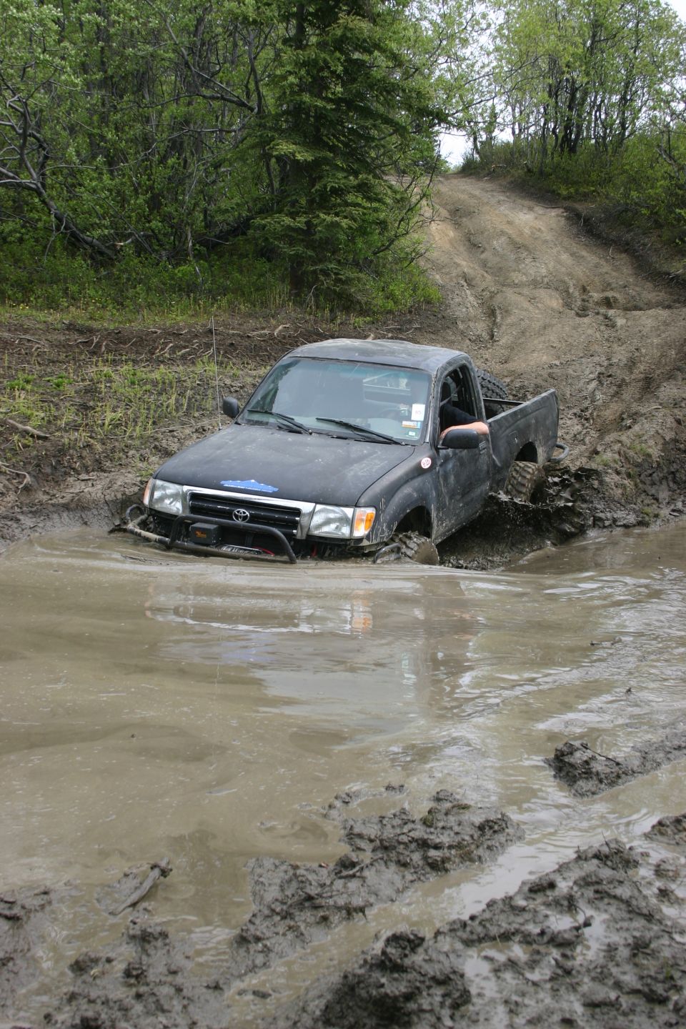Black pickup truck stuck in mud hole on off-road trail