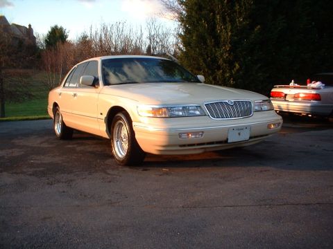 1996 Mercury Grand Marquis - Front view of a cream-colored sedan with a chrome grille, parked outdoors.
