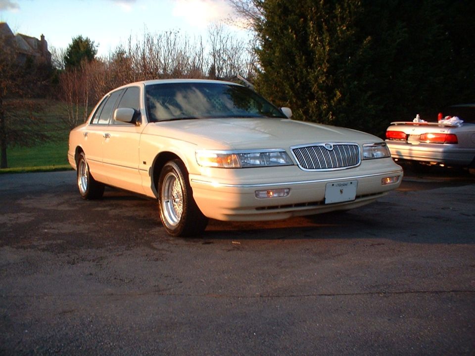Cream Mercury Grand Marquis sedan, three-quarter front view with chrome waterfall grille