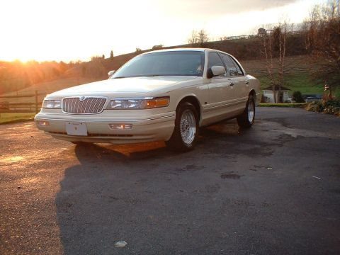1996 Mercury Grand Marquis - A 1996 Mercury Grand Marquis is parked outside during a sunset with hills in the background.