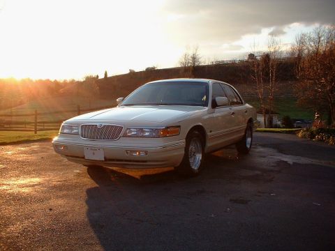 1996 Mercury Grand Marquis - Cream-colored 1996 Mercury Grand Marquis in three-quarter front view during golden hour.