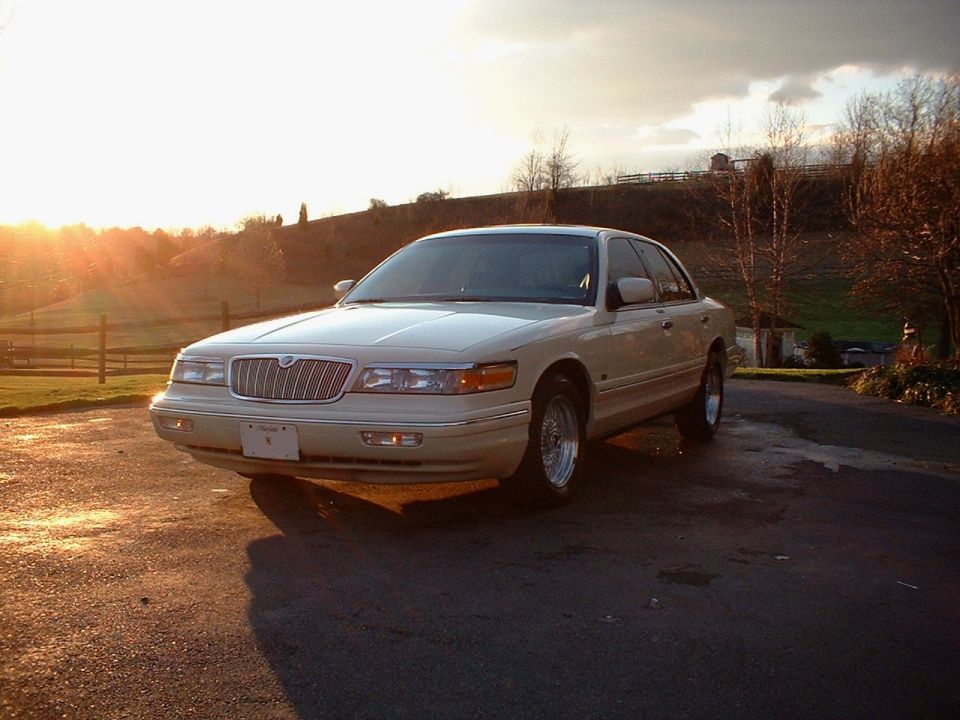 White Mercury Grand Marquis sedan, front 3/4 view at sunset on paved lot