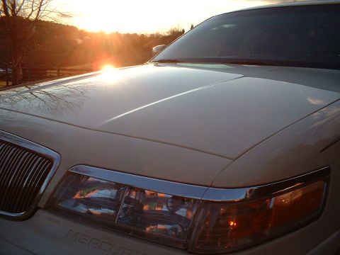 1996 Mercury Grand Marquis - The sun sets behind a 1996 Mercury Grand Marquis, highlighting its hood and grille.