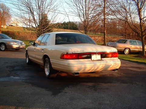 1996 Mercury Grand Marquis - Rear view of a beige 1995 Mercury Grand Marquis sedan parked outdoors with another car visible in the background.