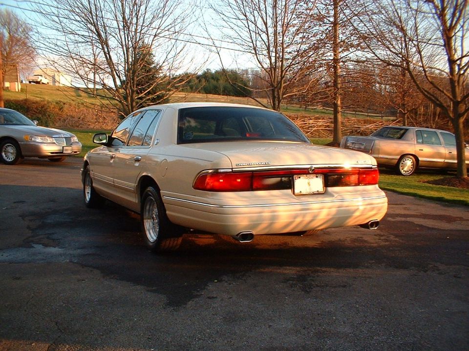 White Mercury Grand Marquis sedan, rear three-quarter view with dual exhaust tips.