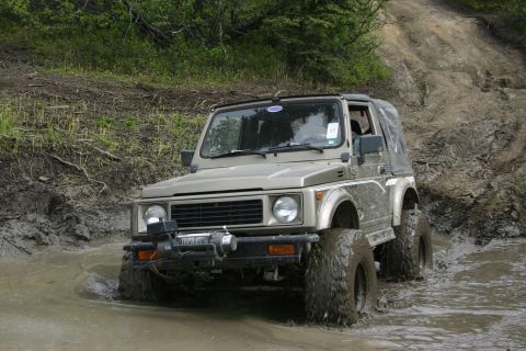 2003 Jeep TJ - This Suzuki Samurai is navigating a challenging muddy terrain, its off-road capabilities.