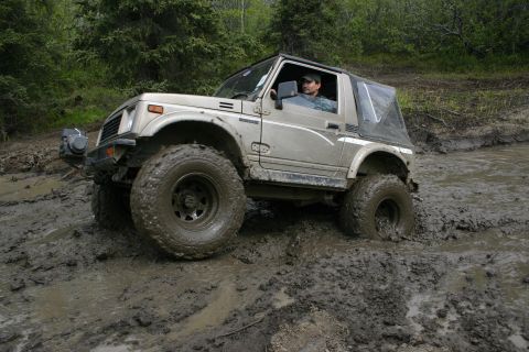 2003 Jeep TJ - A driver navigates a muddy off-road trail in a Suzuki Samurai.