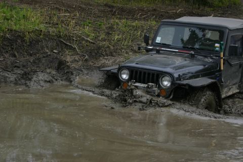 2003 Jeep TJ - A Jeep Wrangler is stuck in a muddy puddle, with only its front half visible.
