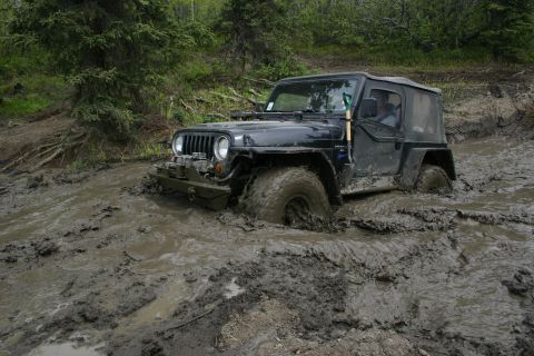 2003 Jeep TJ - A black 2003 Jeep TJ is stuck in deep mud during an off-road event.