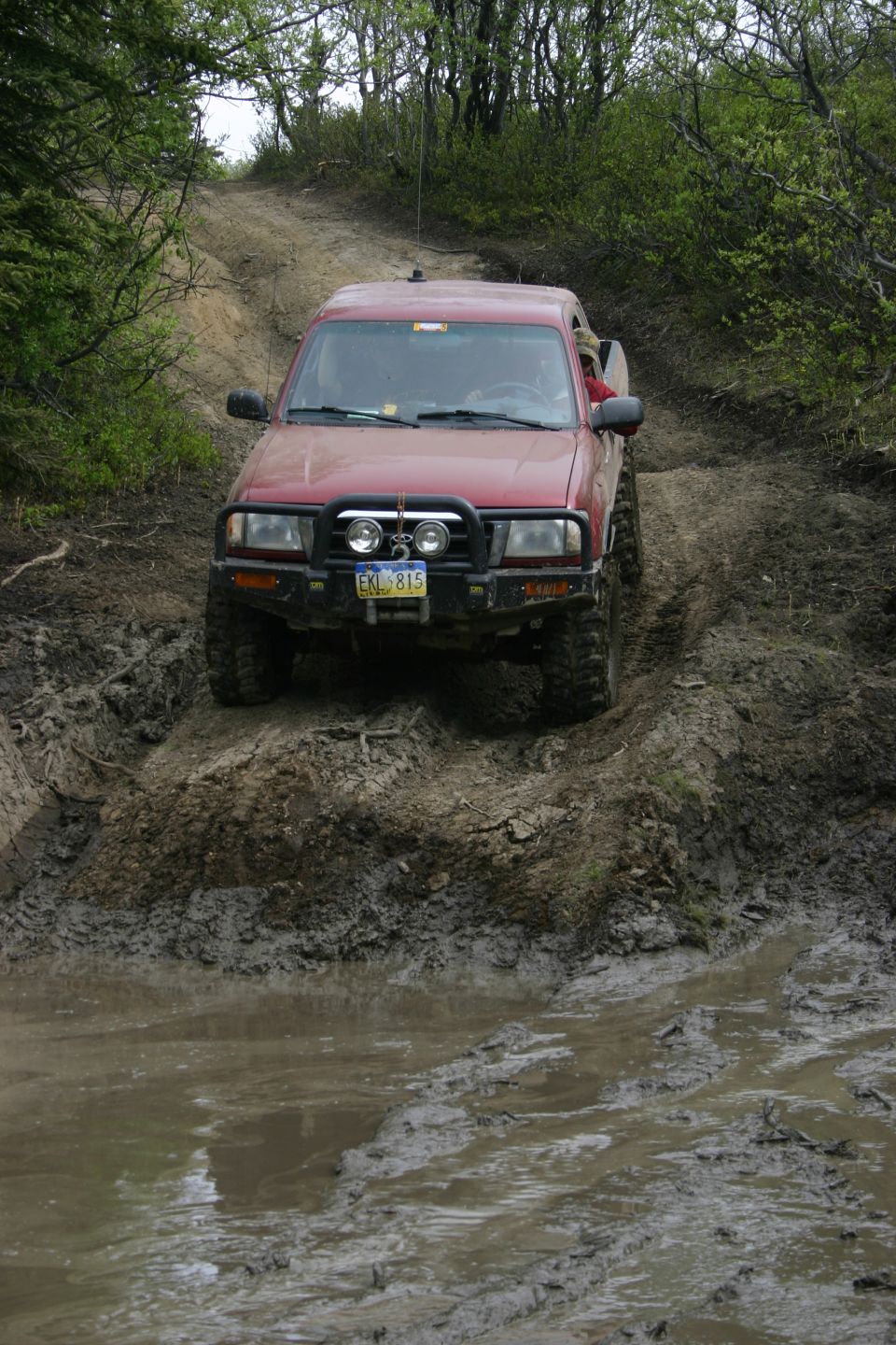 red pickup truck going through mud on a trail