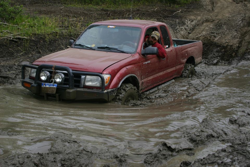 Red pickup truck stuck in mud with driver visible