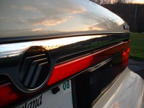 1996 Mercury Grand Marquis - The rear of a Mercury Grand Marquis is captured at sunset, reflecting the sky.