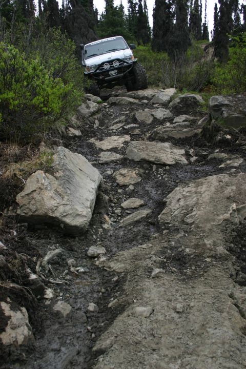 2003 Jeep TJ - A 2003 Jeep TJ tackles a challenging off-road path with steep inclines and large rocks.