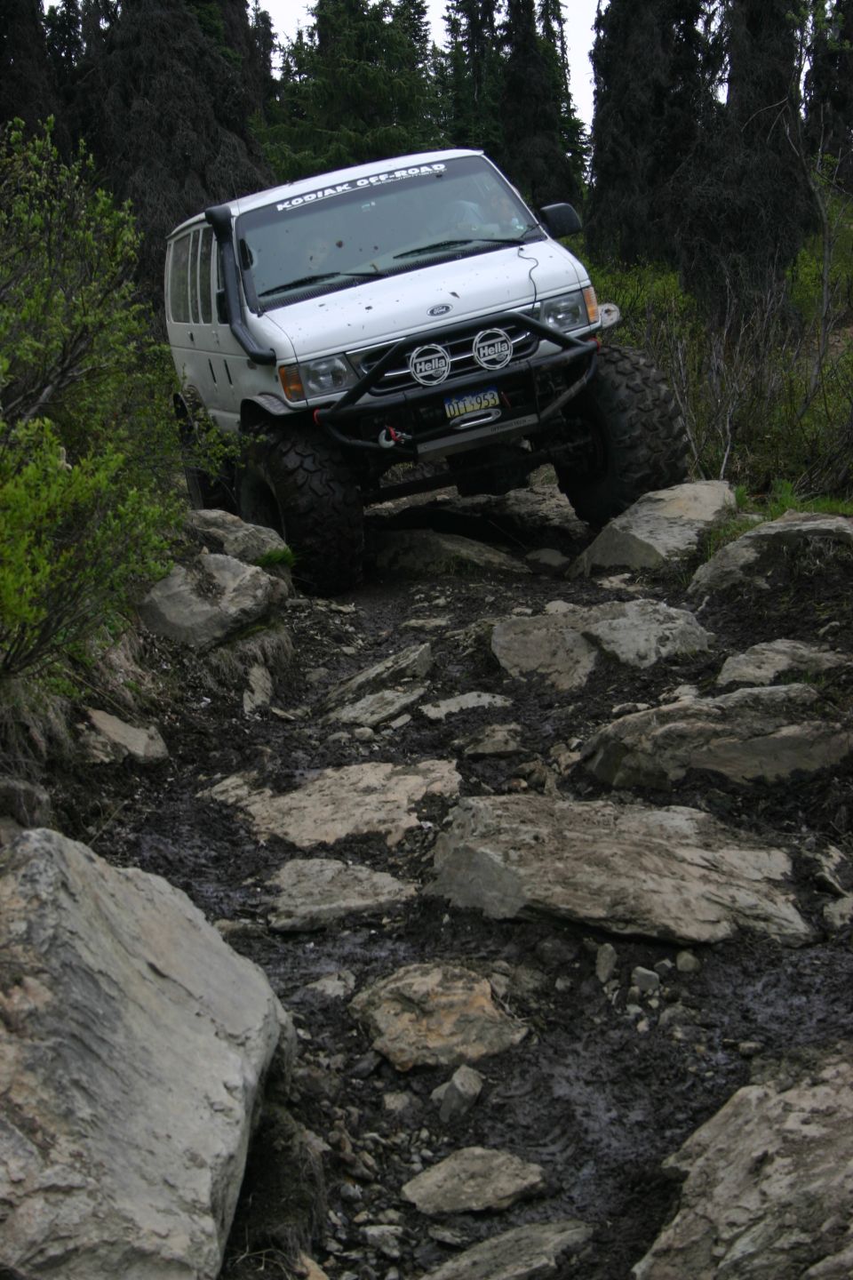 White van with off-road tires navigating a rocky trail