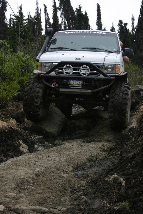 2003 Jeep TJ - This modified van navigates a challenging off-road path through a wooded area.