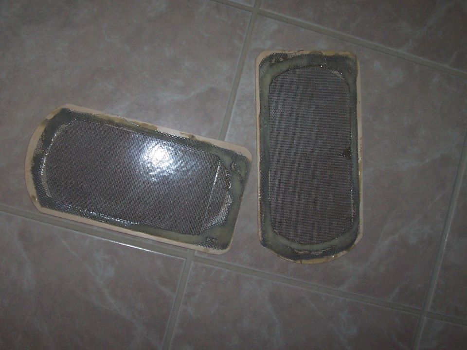 Two oval mesh screen vent or vapor canister filter pieces with sealant on tile floor