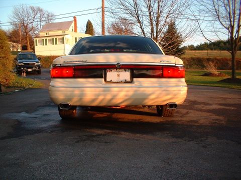 1996 Mercury Grand Marquis - The rear of a cream-colored Mercury Grand Marquis is shown with dual exhaust pipes and a license plate.