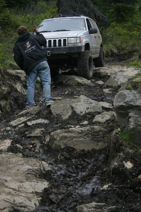 2003 Jeep TJ - A Jeep Grand Cherokee navigates a challenging off-road course with a guide assisting.