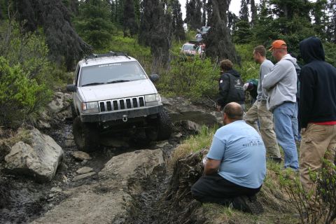 2003 Jeep TJ - A group watches a silver Jeep Grand Cherokee tackle a challenging off-road course.