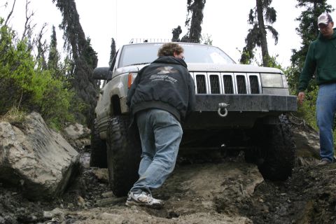 2003 Jeep TJ - A Jeep Grand Cherokee navigates a challenging off-road course with rocky terrain and mud.