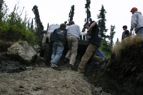 2003 Jeep TJ - A group of off-road enthusiasts attempts to free a stuck Jeep Wrangler from a challenging muddy terrain.