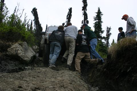 2003 Jeep TJ - People push a stuck Jeep TJ on a muddy trail.