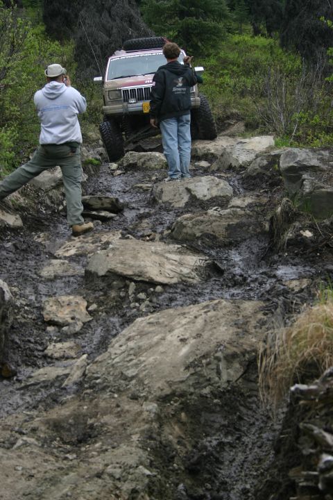 2003 Jeep TJ - A Jeep Cherokee XJ navigates a challenging off-road course, with spectators observing the action.
