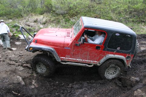 2003 Jeep TJ - A red 2003 Jeep Wrangler TJ navigates a challenging muddy off-road course.