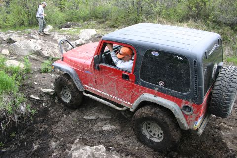 2003 Jeep TJ - Jeep TJ tackling a challenging off-road course with a driver and spotter present.