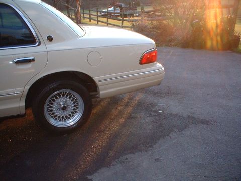 1996 Mercury Grand Marquis - Rear view of a beige 1996 Mercury Grand Marquis, showing its distinctive body style and chrome accents in the late afternoon sun.