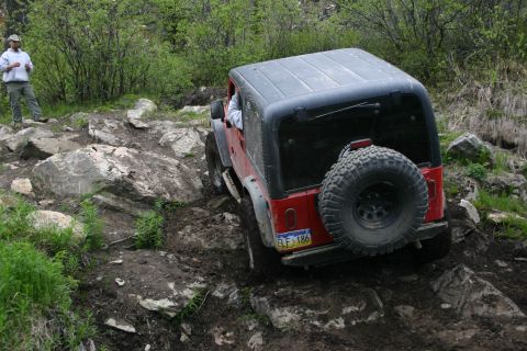 2003 Jeep TJ - 2003 Jeep TJ tackling a challenging off-road course with steep inclines and large rocks.