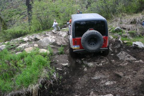 2003 Jeep TJ - A red Jeep Wrangler navigates a challenging, rocky off-road trail.
