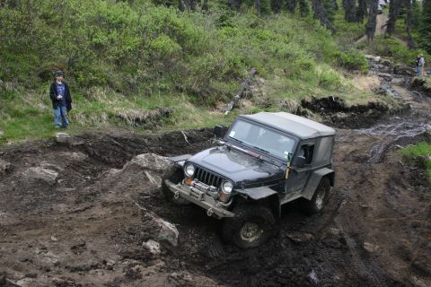 2003 Jeep TJ - A 2003 Jeep TJ tackles a challenging muddy and rocky off-road path.