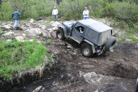 2003 Jeep TJ - A Jeep TJ is shown tackling a challenging off-road course with spectators observing the action.