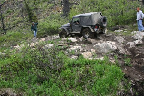 2003 Jeep TJ - A black Jeep Wrangler TJ navigates a challenging rocky trail during an off-road event.