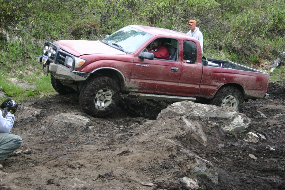 Red 2003 Toyota Tacoma navigating a difficult off-road course
