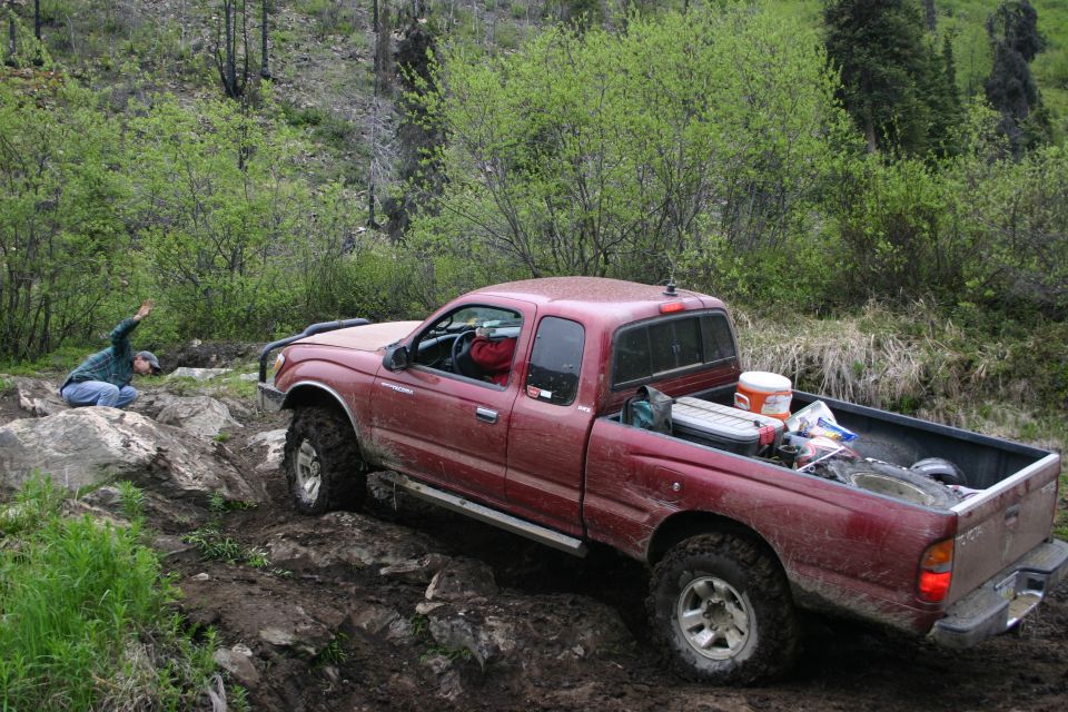 Red Toyota Tacoma pickup truck navigating rocky terrain