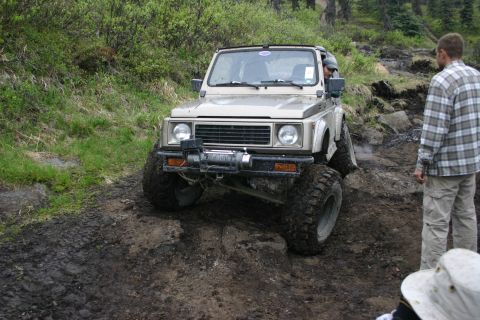 2003 Jeep TJ - A tan Suzuki Samurai navigates a challenging muddy off-road course.