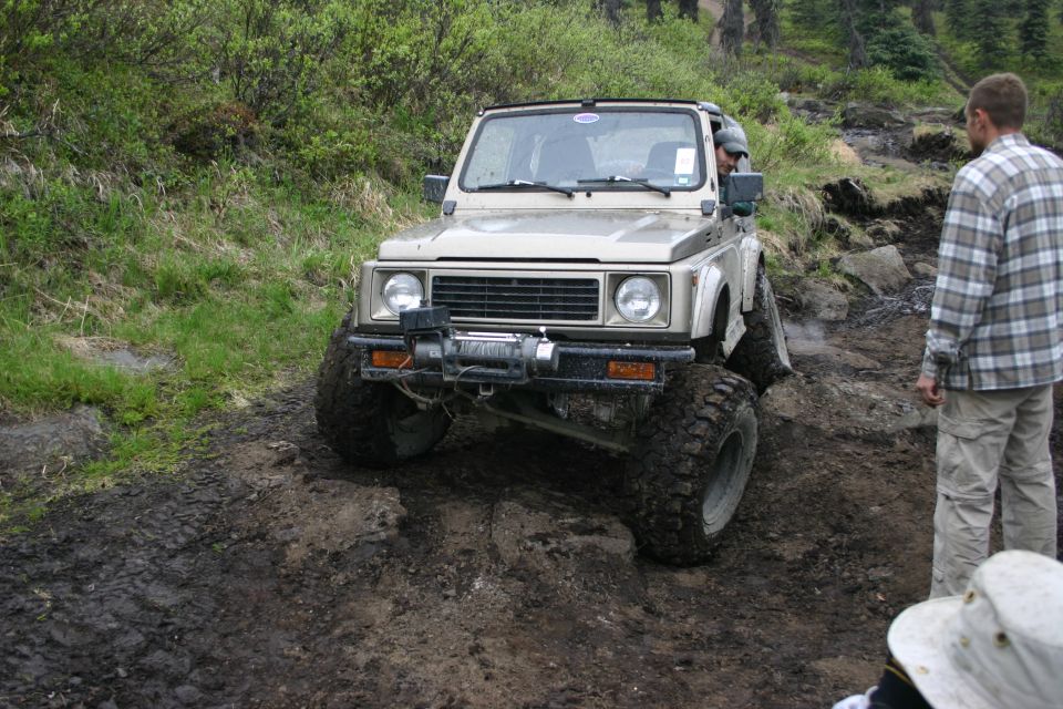Tan Suzuki Samurai off-roading on a muddy trail with a winch mounted on the front bumper