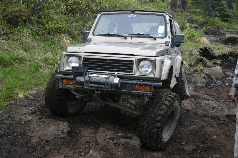Tan off-road SUV with winch on front bumper, navigating rocky terrain