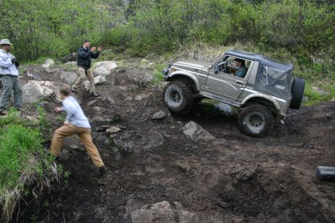 2003 Jeep TJ - Suzuki Samurai tackles a challenging off-road course with spectators observing the action.